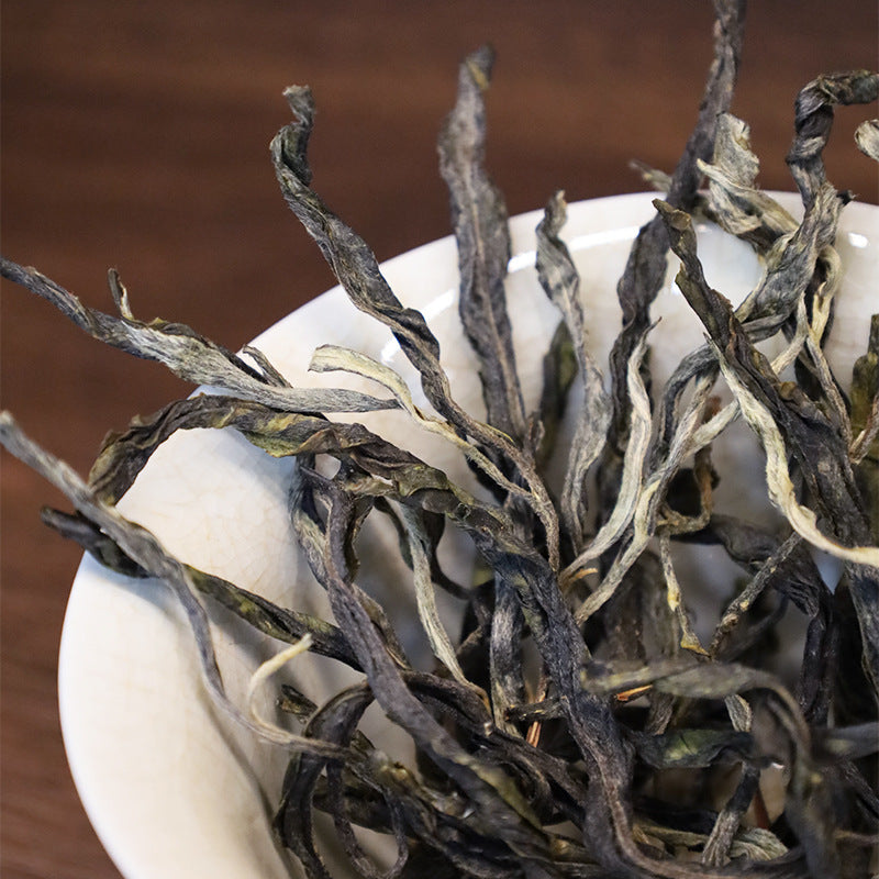 Dry Lvshuitang sheng pu-erh tea leaves in a gaiwan — long twisted strips with white downy tips, high-altitude Lincang Chinese tea, 2025 spring harvest
