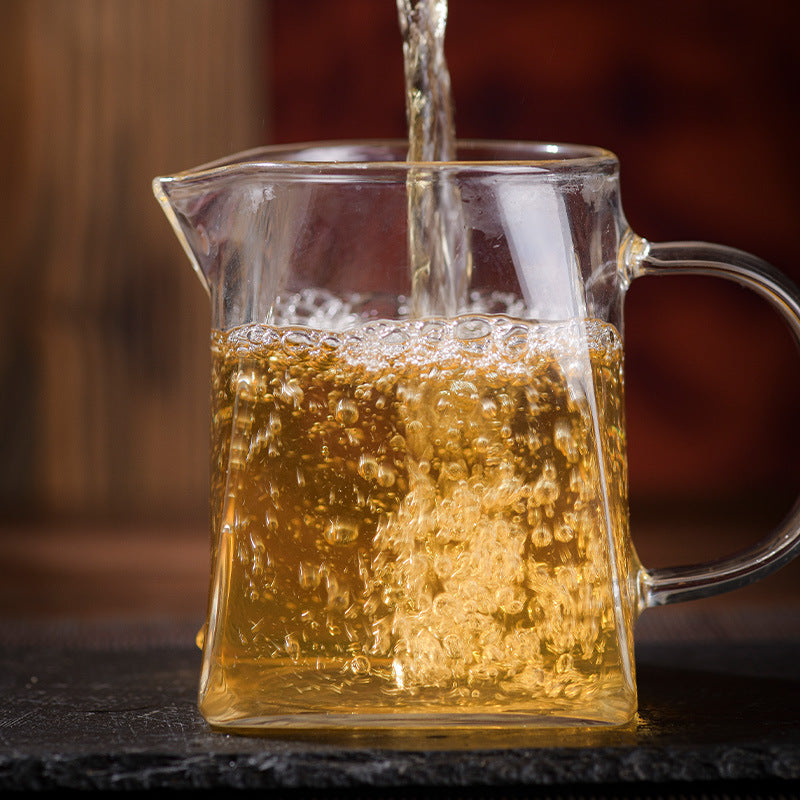 Golden Lvshuitang sheng pu-erh tea liquor pouring into glass gongdao cup — crystal-clear Lincang Chinese raw puerh infusion, rock-sugar sweetness and wild fragrance

