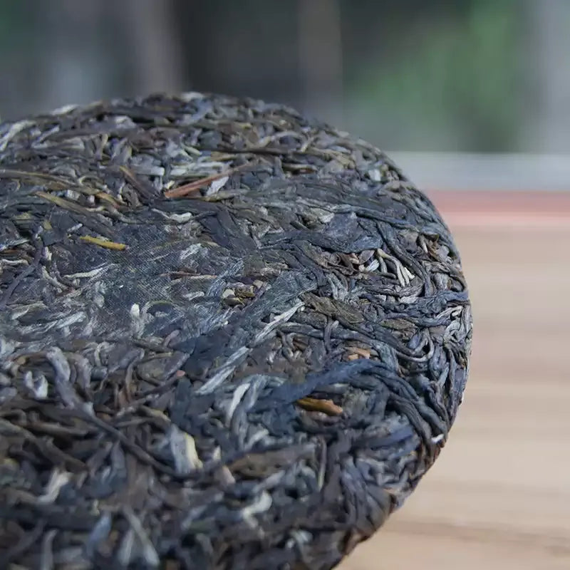 Nahan 2025 sheng pu-erh cake surface detail, silver-white buds visible dark green leaves Bangdong Lincang Yunnan China