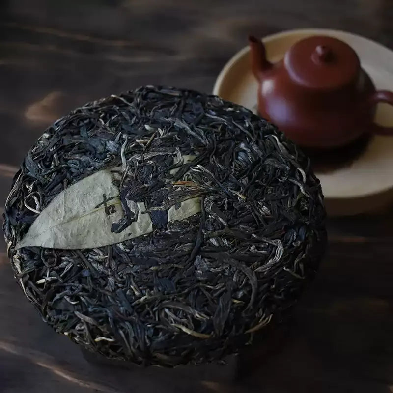 Zhengqitang 2025 raw pu-erh cake top view, old tree sheng puerh dry leaf texture stone-pressed Mengku Yunnan
