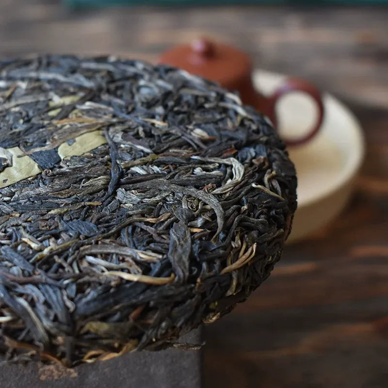 Zhengqitang 2025 raw pu-erh cake side detail closeup, old tree pressed sheng puerh leaf structure Yunnan
